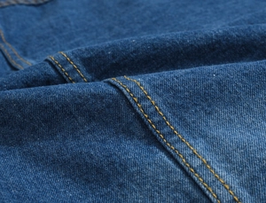Close-up of winter denim jacket fabric featuring thick blue cotton and yellow stitching