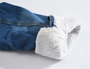 Close-up of men's denim jacket cuff with thick white faux shearling lining and orange stitching