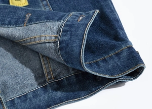 Close-up of dark blue denim vest collar featuring classic yellow double stitching details