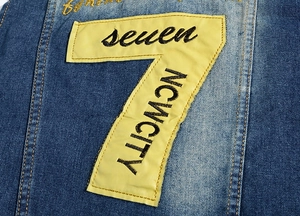 Close-up of yellow number 7 patch with premium black embroidery on blue denim vest