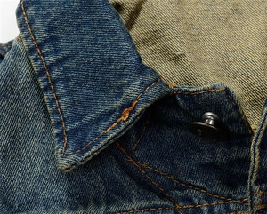 Detailed close-up of heavy wash denim collar with orange contrast double stitching