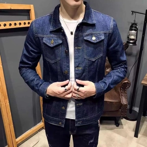 Detail of dark blue denim jacket featuring classic flap chest pockets and metallic buttons