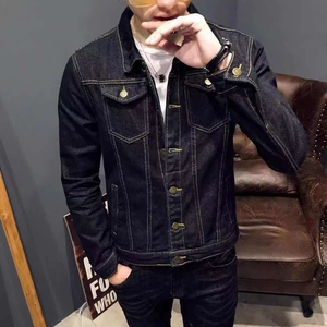 Detail of dark wash denim jacket featuring classic chest pockets and bronze buttons