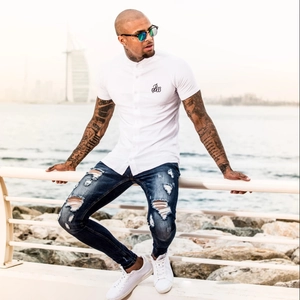 Detail der schmal geschnittenen blauen Jeans mit Rissen und einem weißen Sommerhemd für Herren