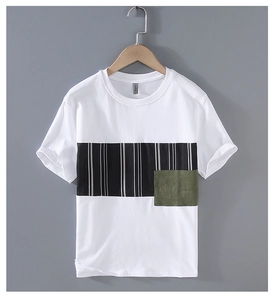 Détail d'un t-shirt blanc en coton avec patchwork à rayures noires et écusson vert olive