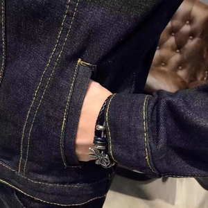 Close-up of retro palm tree pendant on black braided leather bracelet for men