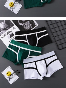 Flat lay of men's cotton boxer briefs in black, green, and white with elastic waistbands