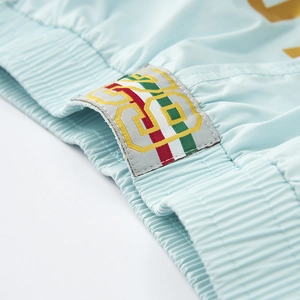 Detail of light blue athletic shorts featuring elastic waistband and colorful woven logo