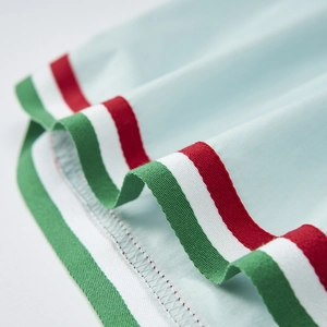 Macro shot of light blue fabric with red white and green striped elastic ribbed cuff detail