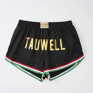 Detail of black sports shorts featuring golden letter print and tricolor striped piping