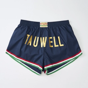 Detail of navy sports shorts with striped edges and gold TAUWELL logo print