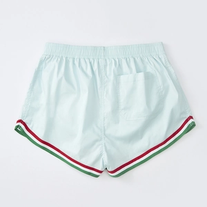 Detail of light blue sports shorts with elastic waist and tricolor stripe edging