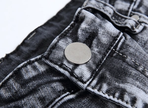 Gros plan sur un jean slim gris pour homme avec bouton en métal argenté et coutures renforcées