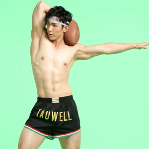 Detail of black sports shorts featuring elastic waistband with tricolor stripes and gold logo