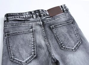 Détail du jean gris ajusté montrant les poches arrière et l'étiquette en cuir
