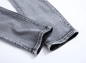 Vue détaillée du bas de pantalon en jean gris avec couture double et texture denim