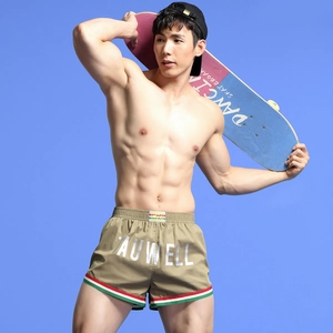 Men's khaki athletic shorts with side stripes and logo detail, shown with skateboard