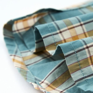 Dettaglio del tessuto a quadri blu e giallo con cuciture rifinite per pantaloncini da uomo