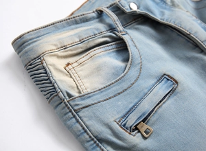 Detail of light blue biker jeans with pleated accordion side and decorative metal zipper