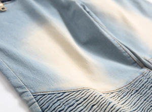 Macro detail of men's biker light blue denim jeans with ribbed pleats and orange stitching
