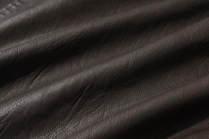 Close-up of premium brown PU leather with natural pebble grain texture on men's vest