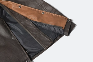 Detail view of brown PU leather vest showing stitching, zipper, and button closure