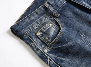 Detail of vintage blue men's jeans with metal rivets and reinforced stitching on pocket
