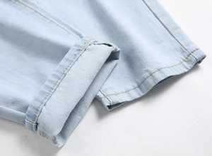 Men's light blue distressed jeans featuring cuffed hems and orange contrast stitching
