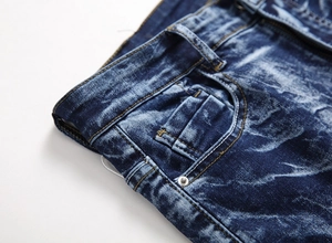 Detail of dark blue washed denim jeans showing pocket rivets and whisker texture