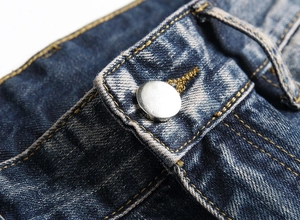 Detailed macro view of vintage blue jeans waistband with silver metal button and amber stitching