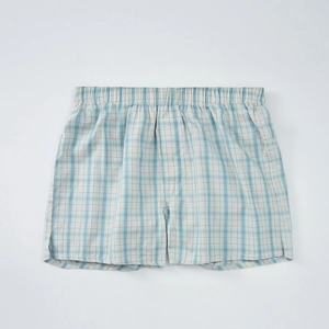 Dettaglio dei boxer a quadretti blu e beige con elastico in vita e trama di cotone