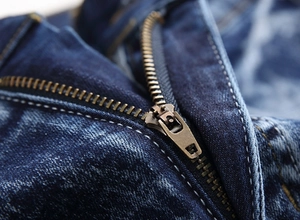 Detailed macro view of metal zipper fly and washed denim texture on men's straight jeans
