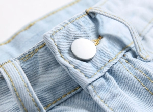 Close-up of light blue denim jeans with yellow stitching and silver metal button detail