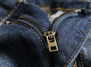 Close-up of vintage bronze zipper detail on high-quality dark blue denim jeans