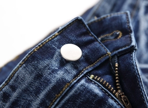 Macro detail of the metal button and zipper on these blue straight-leg washed jeans