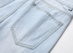 Detail of light blue denim fabric featuring yellow contrast stitching and a rear pocket