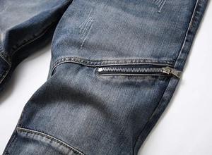 Detail of blue jeans featuring decorative metal zippers and faded whiskers on denim fabric