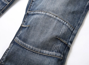 Detail of dark blue denim jeans with reinforced stitching and vintage distressed fade