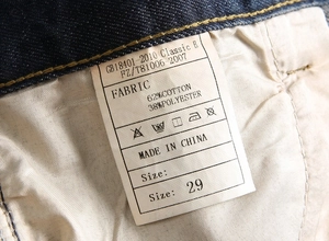 Detail of blue jeans laundry label showing 62% cotton and 38% polyester composition
