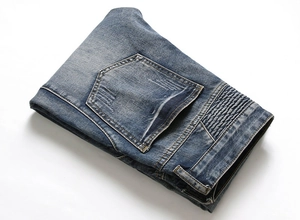 Detail of men's blue jeans featuring biker-style pleated panels and washed denim texture