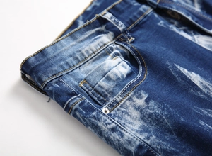 Detailed view of dark blue snow-wash jeans with yellow stitching and metal rivets