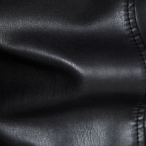 Gros plan sur la texture du cuir PU noir avec grain litchi et détails de couture précis