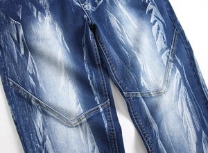 Detailed close-up of dark indigo denim with heavy white wash and contrast orange stitching