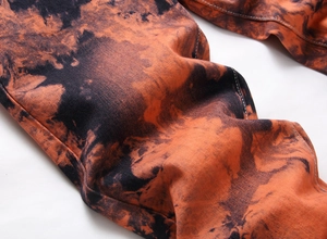 Dettaglio del tessuto dei jeans da uomo con motivo tie-dye arancione e cuciture bianche