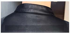 Close-up of vintage black faux leather jacket showing stand collar and back stitching texture