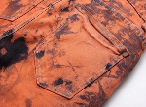 Dettaglio del tessuto denim tie-dye arancione e nero con cuciture sulla tasca posteriore