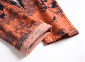Dettaglio jeans tie-dye arancio e nero con risvolti sul fondo e cuciture di alta qualità