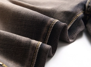 Macro shot of dark grey denim fabric with yellow contrast stitching and twill texture