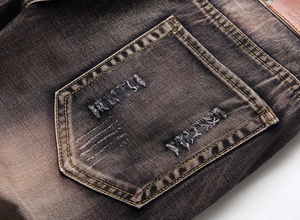 Close-up of distressed back pocket with yellow stitching and embroidery on denim jeans