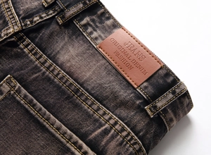 Close-up of vintage washed denim waistband with brown faux leather patch and gold stitching